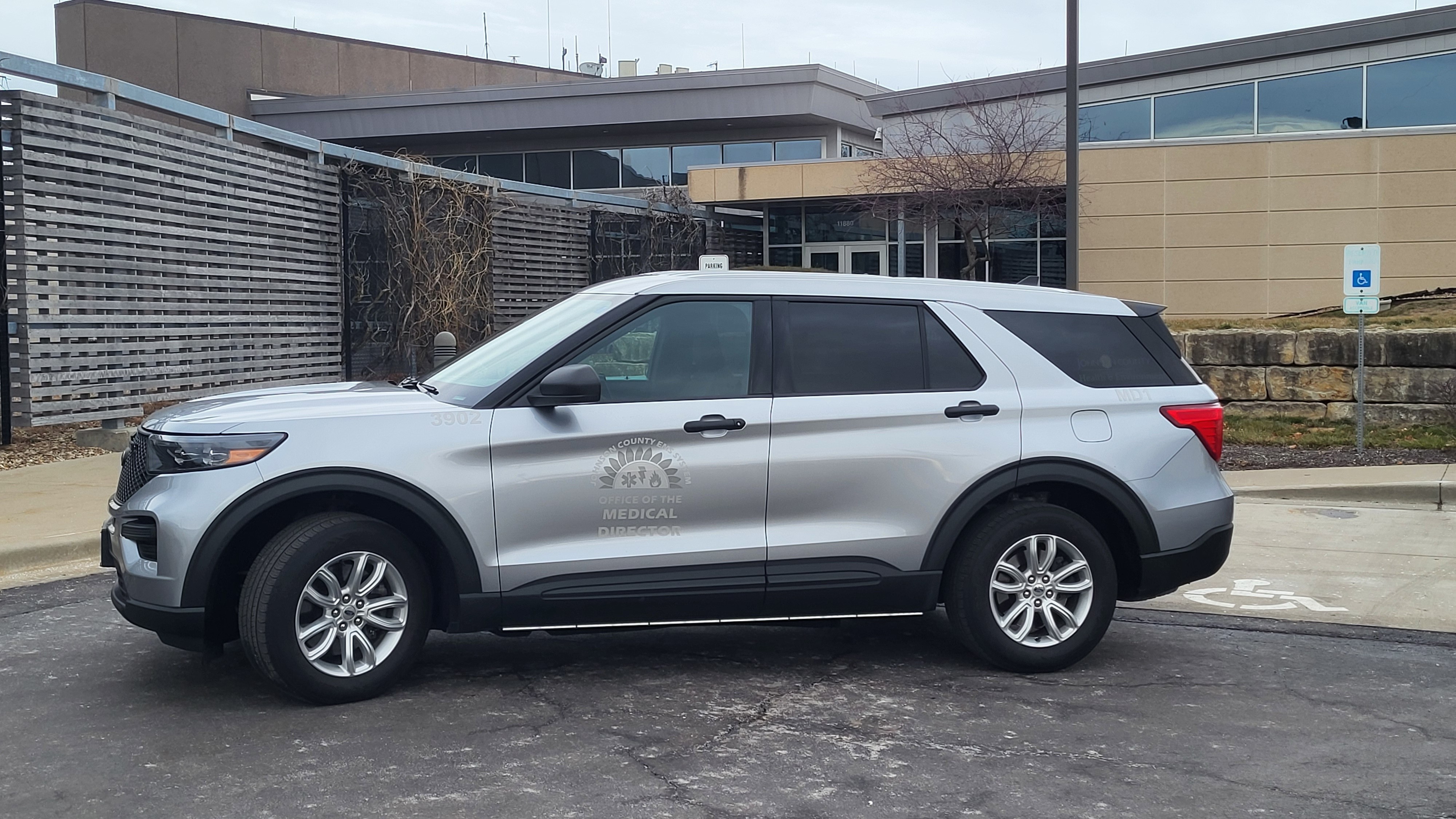 A grey four door car in front of a building